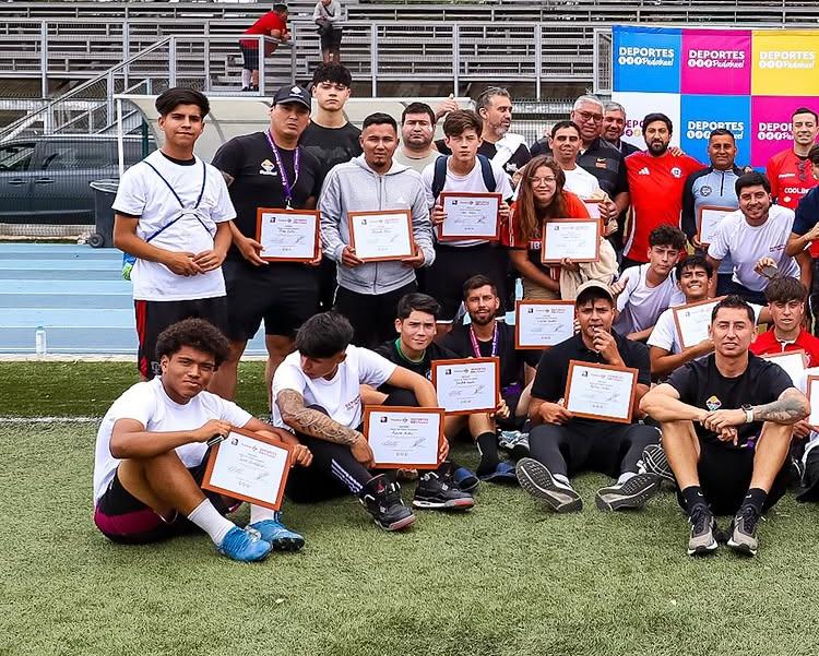 Grupo de entrenadores en la cancha mostrando sus certificados del curso