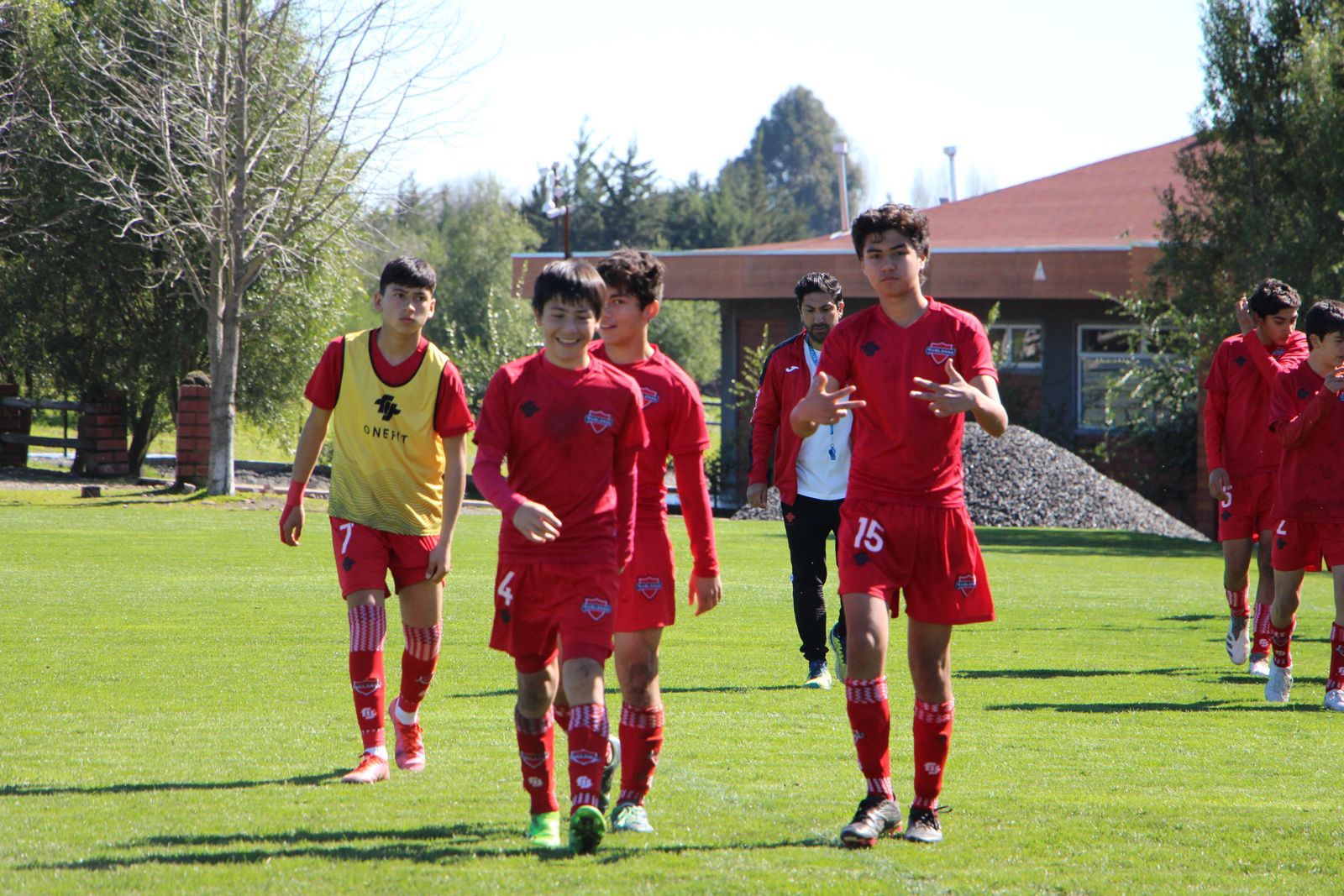 Jugadores juveniles de camiseta roja caminando por la cancha después de un partido