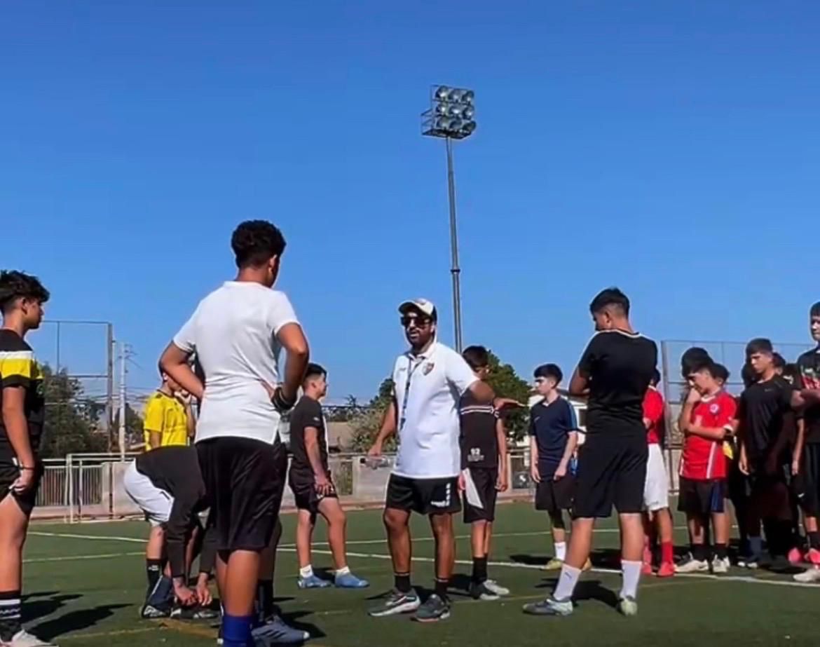 Williams Olave dando instrucciones a un grupo de jugadores juveniles en la cancha